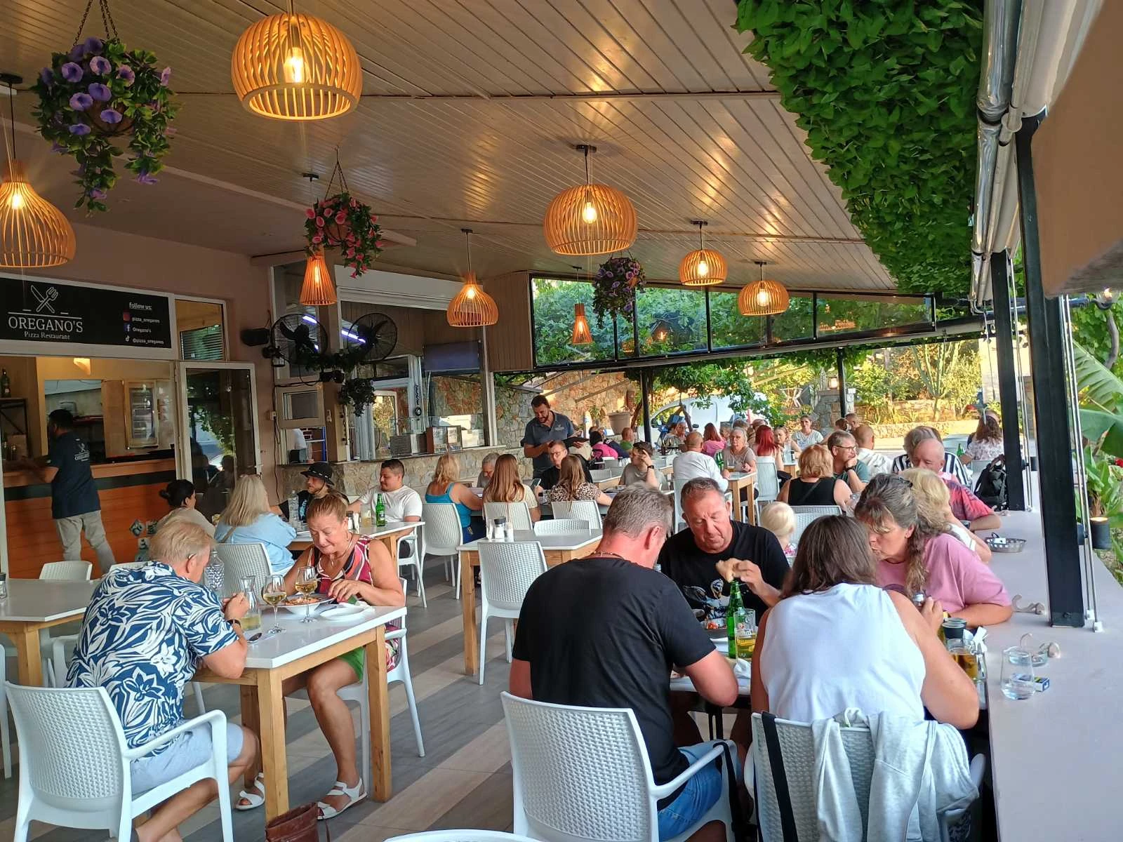 Oregano’s Pizza Restaurant in chania outdoor space while costumers enjoy fresh pizza , pasta, grill and more located near the beach in Chania, Crete.