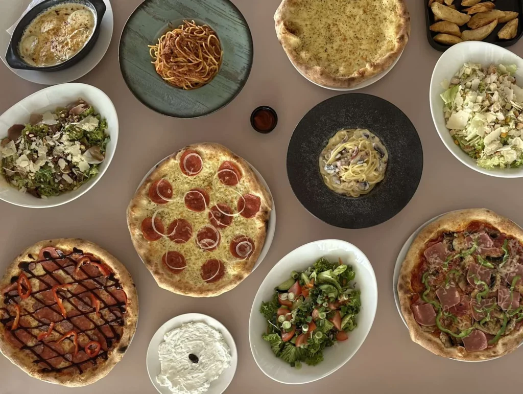 A variety of authentic Italian and Greek cuisine dishes, including artisanal pizzas, fresh salads, and creamy pasta at Oregano's Restaurant, the best food in Chania.